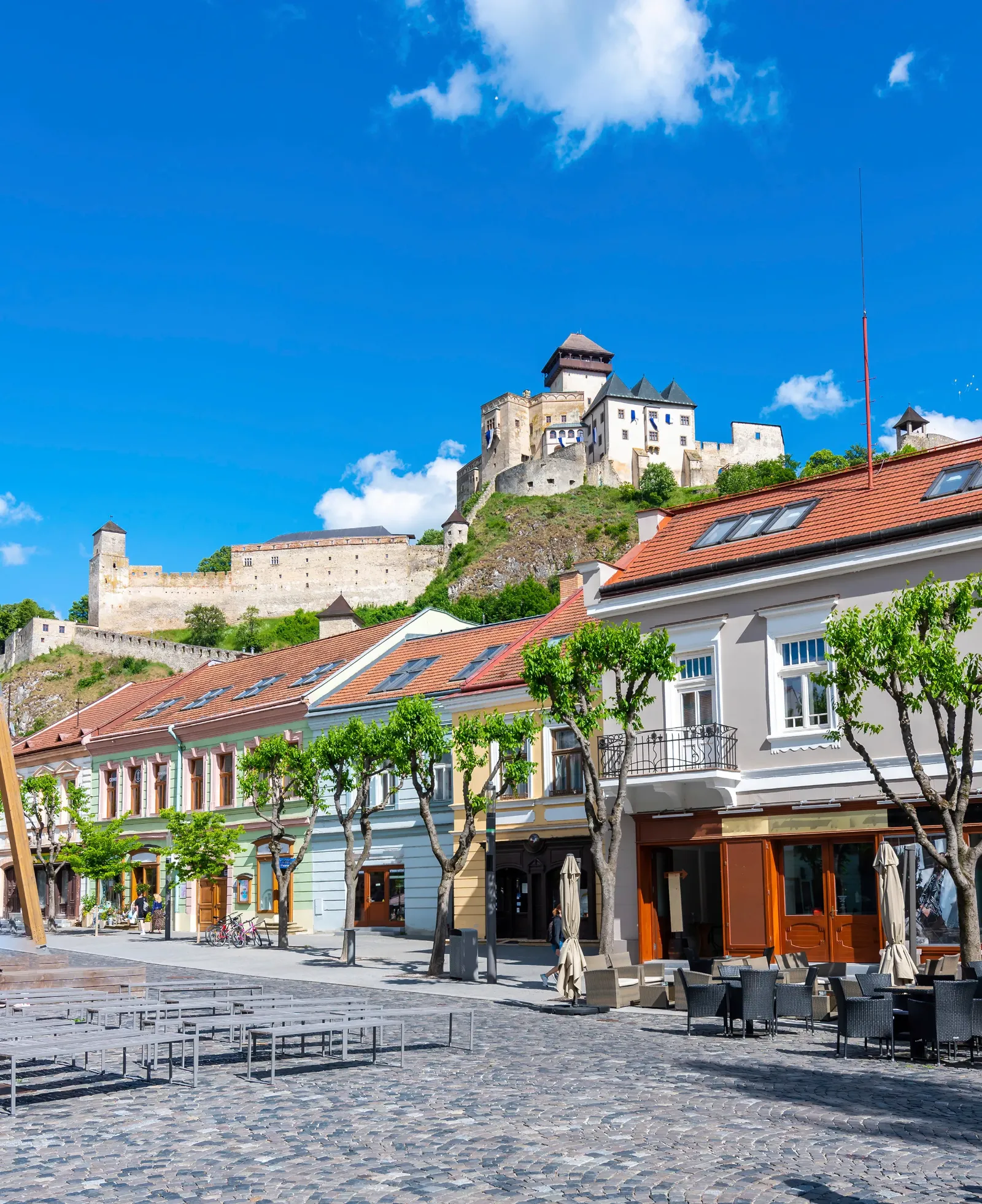 Einige Häuser in der Altstadt der slowakischen Stadt Trencin sind zu sehen, über der die weiße Burg trohnt.