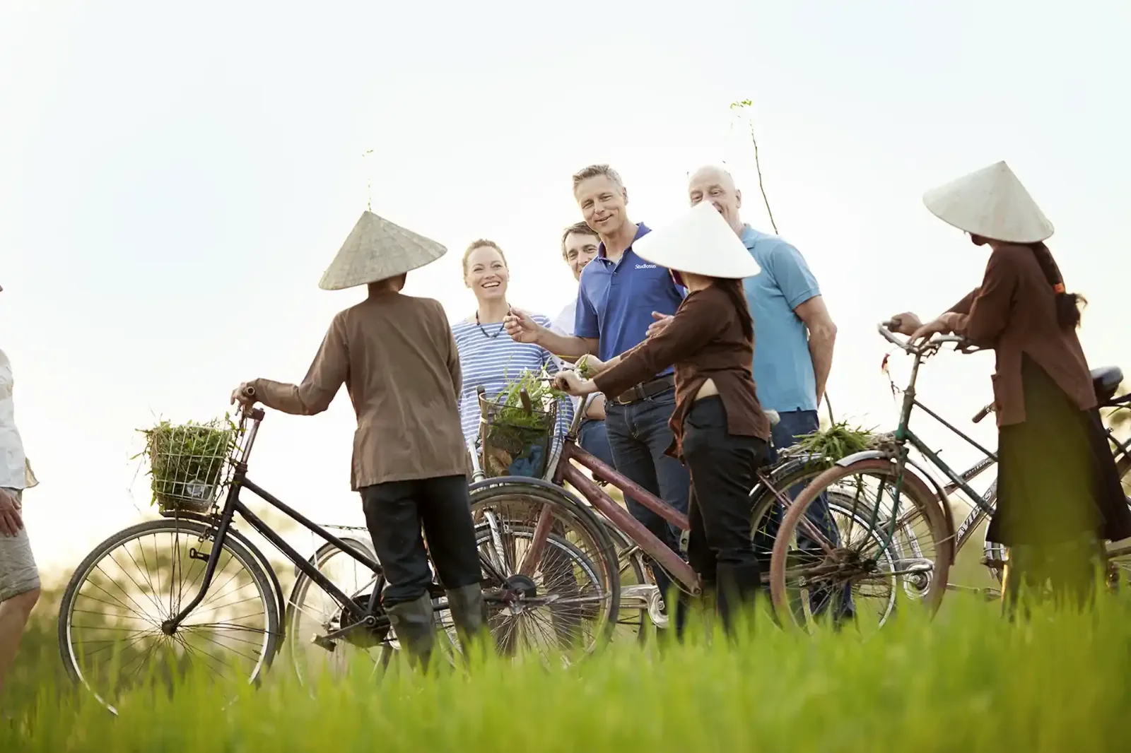 Eine Gruppe von Menschen, die in einem Feld mit Fahrrädern stehen.