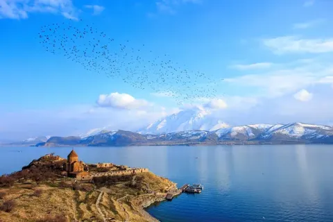 Der Vansee in der Osttürkei ist zusammen mit einer Landzunge im Vordergrund und dem Bergpanorama im Hintergrund zu sehen.