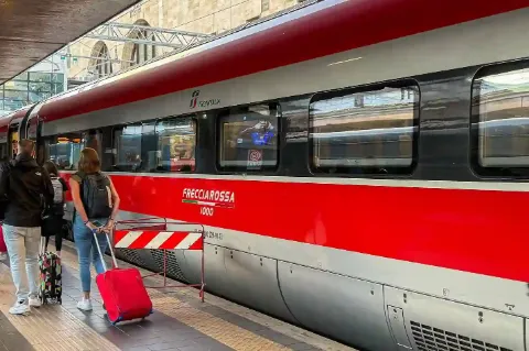Nahaufnahme eines italienischen Frecciarossa Zuges am Bahnhof mit Reisenden am Bahnsteig.