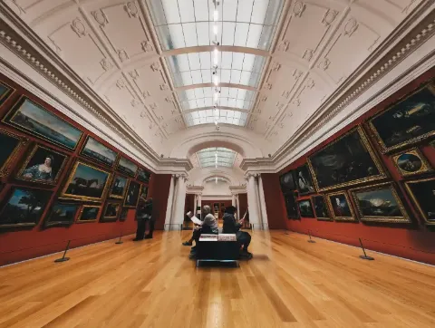Innenansicht einer Kunstgalerie mit Gemälden an den Wänden.