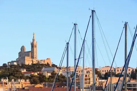 Der Alte Hafen in Marseille mit Blick auf die Kathedrale Notre-Dame-de-la-Garde, die hoch oben auf einem Hügel über der Stadt thront.