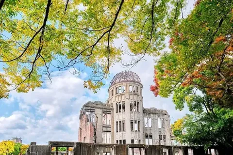 Eine Ruine von einem Gebäude zwischen Bäumen im Friedenspark in der japanischen Stadt Hiroshima.