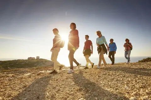 Eine Gruppe von Menschen beim Wandern in der Natur während eines Sonnenuntergangs.