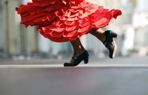 Nahaufnahme von Schuhen unter einem schwingenden Kleid.