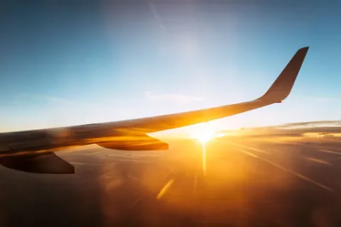 Blick auf einen Flugzeugflügel, den Himmel und die Wolken von einem Flugzeug aus.
