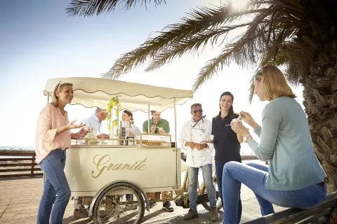 Die Reisegruppe steht um einen Eiswagen herum und genießt die Süßspeise. 