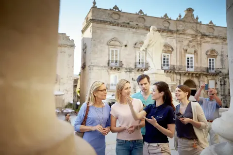 Gäste lauschen der Reiseleiterin bei einen Stadtführung.