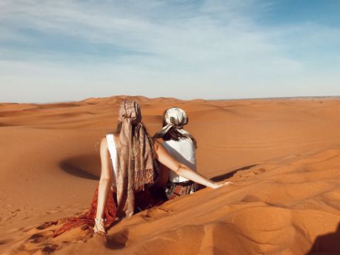 Zwei Frauen sitzen in der Wüste und genießen die Aussicht.