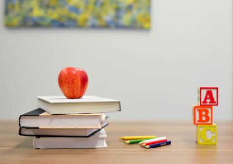 Lernmaterialien mit einem Apfel und Bausteinen auf einem Tisch.