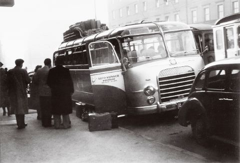 Historischer Reisebus mit Gepäck auf dem Dach in einer Stadt