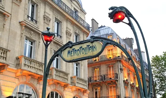 Eingangsbereich der Pariser U-Bahn mit beleuchtetem Metropolitain-Schild im Art Nouveau-Stil.