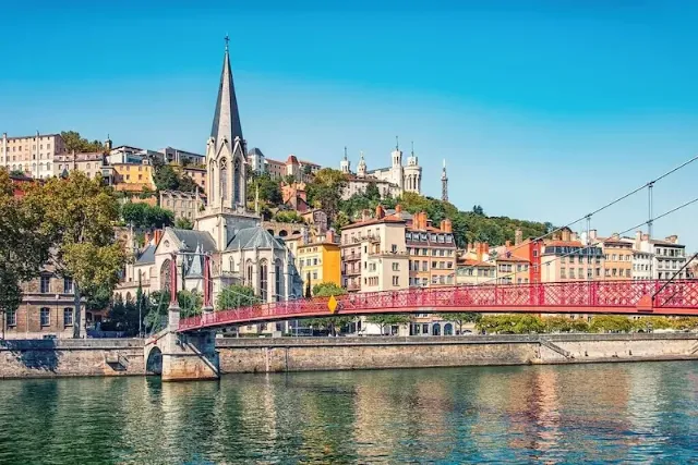 Die Altstadt von Lyon am Ufer des Saone Flusses mit einer Kirche und einem bebauten Hügel.