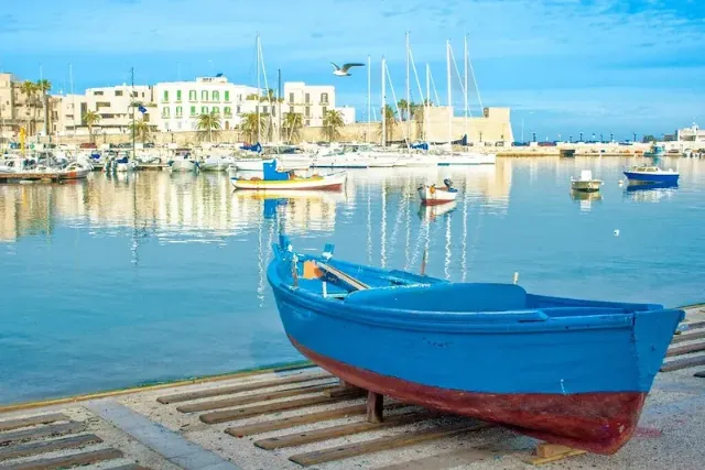 Der Hafen von Bari bei sonnigem Wetter mit einem blauen Ruderboot im Vordergrund.