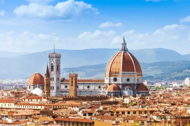 Der Dom von Florenz im sonnigen Wetter mit den Bergen der Apenninen im Hintergrund.