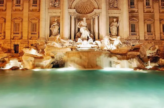 Der Trevi-Brunnen in Rom bei Nacht mit beleuchteten Wasserspielen.