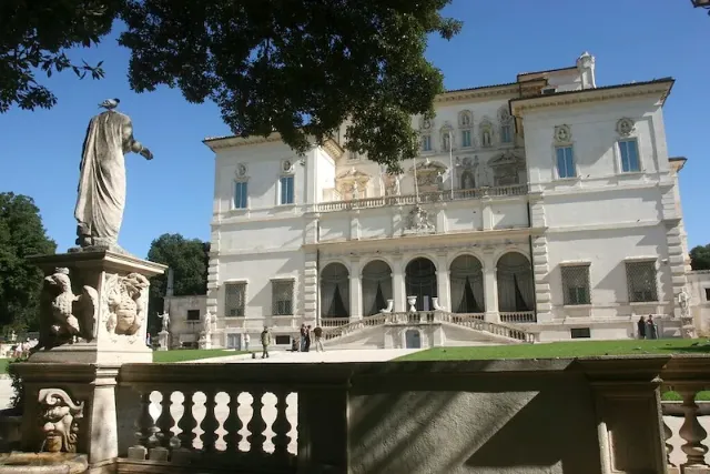 Ansicht der Villa Borghese in Rom mit einer Statue und Garten im Vordergrund.