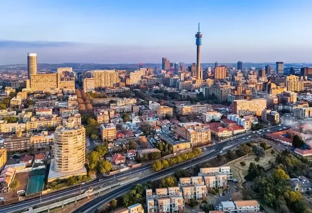 Die südafrikanische Hauptstadt Johannesburg mit den markanten Ponte-Hochhäusern und dem Fernsehturm, bei Sonnenuntergang.
