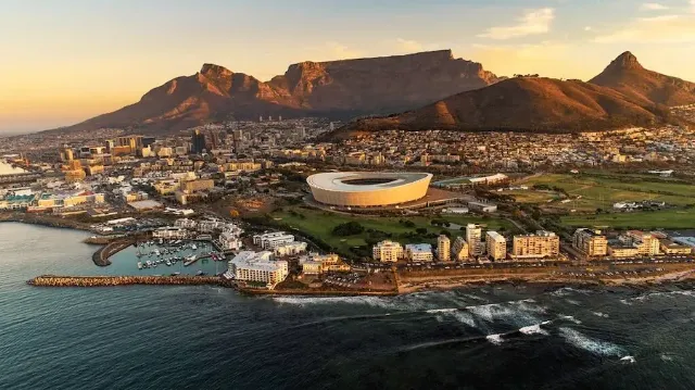 Ein Panoramablick auf Kapstadt und dem Tafelberg in Südafrika, mit Gebäuden und einem Sportstadion im Vordergrund.