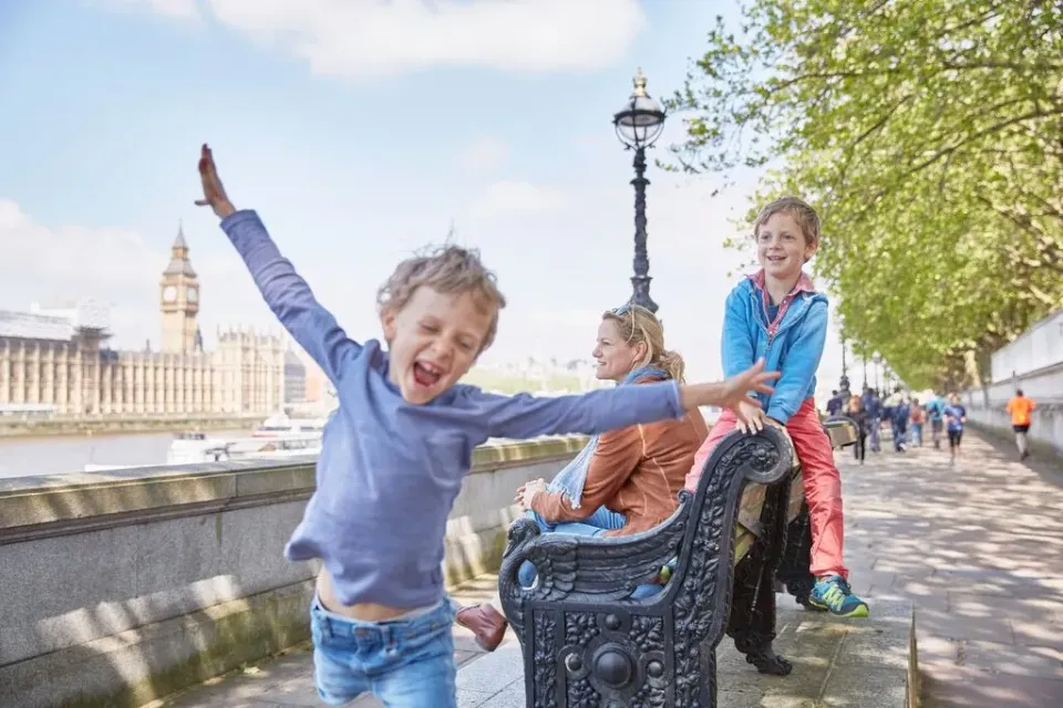 Eine Mutter mit zwei Kindern auf einer Bank in der Nähe des Big Ben in London.