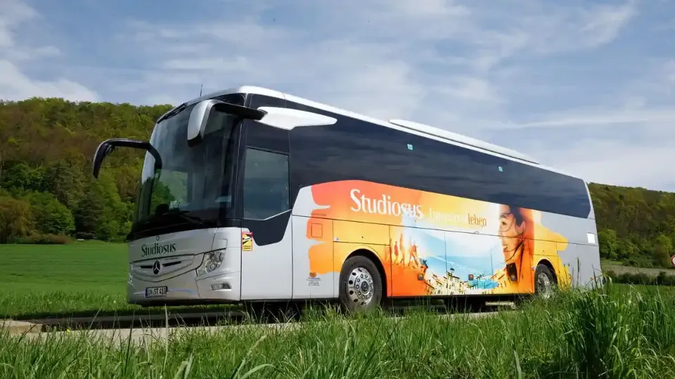 Ein moderner Reisebus von Studiosus fährt auf einer Landstraße.