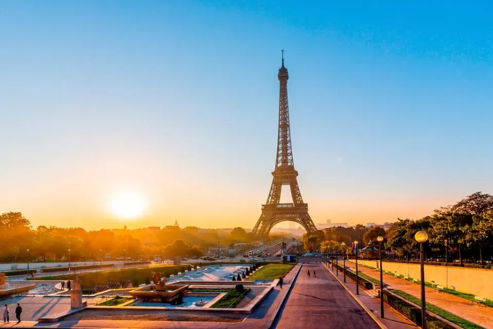 Der Eiffelturm in Paris in der Abenddämmerung mit untergehender Sonne.