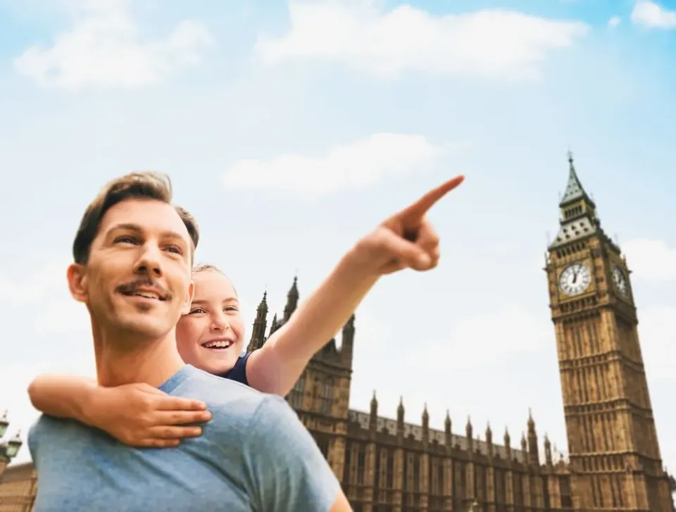 Ein Mädchen sitzt auf dem Rücken ihres Vaters und schaut begeistert vor dem Big Ben Turm in London.
