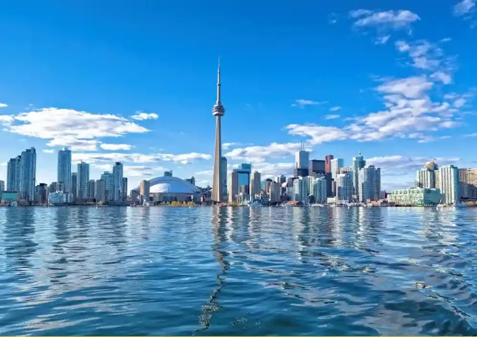 Hochhäuser von Toronto unter leicht bewölktem Himmel und umgeben von Wasser.