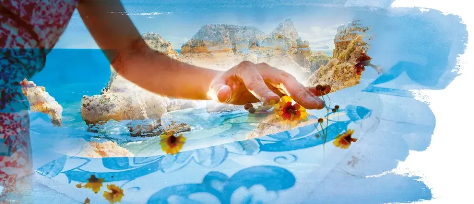 Eine Bildkollage mit einer Hand, die sanft Blumen am Strand in einer schönen sonnigen Landschaft berührt.
