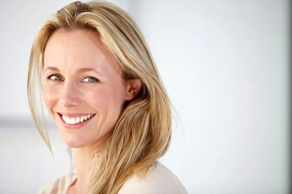 Eine blonde Frau lacht in die Kamera.