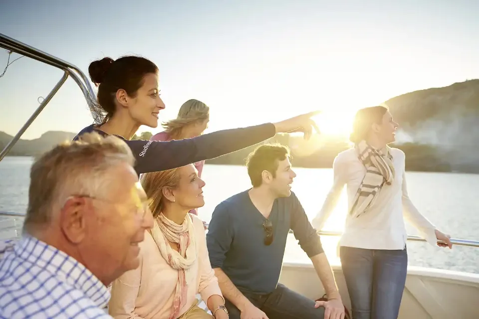 Eine Gruppe von Personen auf einem Boot beim Sonnenuntergang.