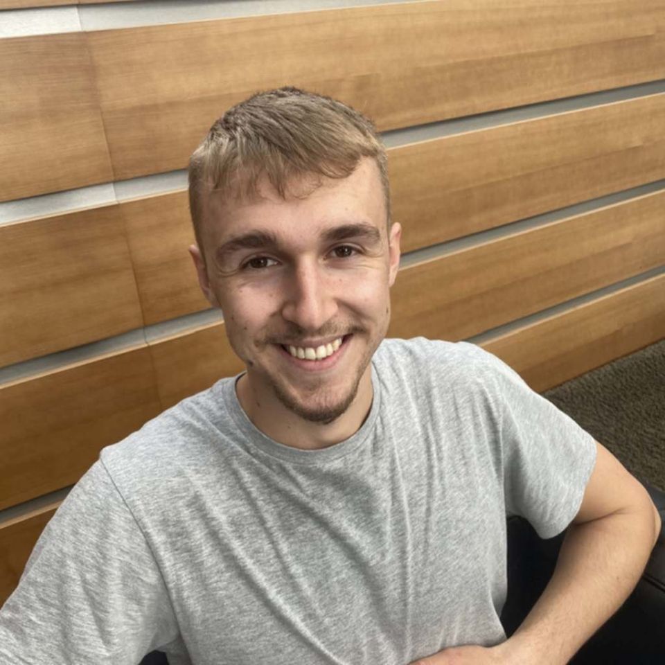 Ein lächelnder junger Mann schaut frontal ins Foto.
