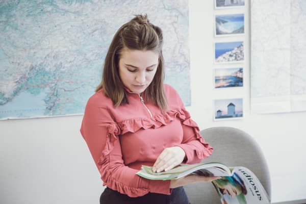 Ein Büro mit einer Weltkarte im Hintergrund und einer Frau, die ein Magazin durchblättert.