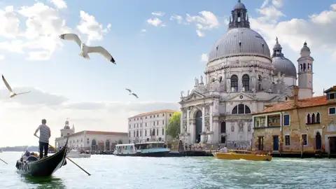Gondolieri auf dem Canal Grande werden Ihnen auf der Städtereise nach Venedig immer wieder begegnen: hier mit der Kirche Santa Maria della Salute im Hintergrund.