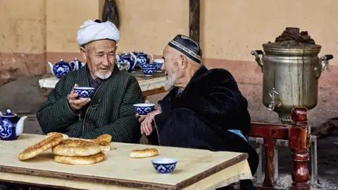 Auf unserer Studienreise Usbekistan - Tagträume im Märchenland treffen wir immer wieder Einheimische. Die blauen Teeschälchen mit Baumwollmuster sind typisch für Usbekistan, die kreisrunden Fladenbrote ebenso.