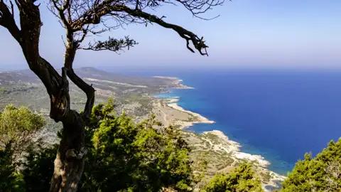 Während unserer Wanderreise durch Zypern erhaschen wir immer wieder einen beeindruckenden Panoramablick auf die Küste von Zypern mit blauem Meer.