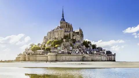 Mont Saint-Michel bei Ebbe, mit sichtbarem Sandstrand und Spiegelung im Wasser