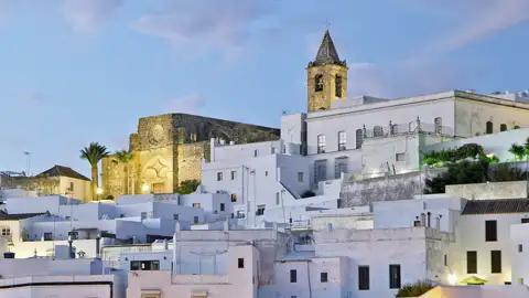 Weiße Häuser und eine Kirche in der andalusischen Stadt Vejer de la Frontera bei Dämmerung