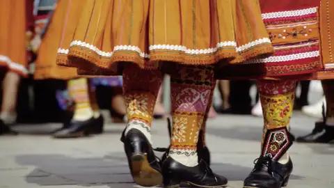 Detailansicht einer traditionellen Tracht Lettlands mit bunten und auffällig gemusterten Röcken und Strümpfen