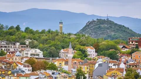 Blick über die Altstadt von Plovdiv während eines Stadtrundgangs, mit traditionellen Häusern,dem Minarett der Dschumaja-Moschee und einem der charakteristischen grünen Hügel der Stadt im Hintergrund.