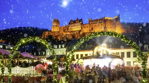 Auf unserer Silvesterreise besuchen wir den Weihnachtsmarkt in Heidelberg mit Buden und Lichtern vor der beleuchteten Burg im Schnee.