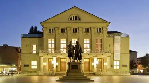 Auf unserer Gruppenreise mit Studiosus besichtigen wir das Deutsche Nationaltheater in Weimar, mit dem beleuchteten Goethe-Schiller-Denkmal im Vordergrund.