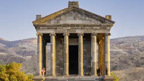 Der römisch-hellenistische Tempel von Garni, eine Sehenswürdigkeit, die auf unserer Armenienreise besichtigt wird, steht vor einer hügeligen Landschaft.