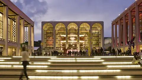 Auf unserer Gruppenreise nach New York bewundern wir die beleuchtete Fassade der Metropolitan Opera bei Dämmerung. Dies ist immer ein Highlight unserer Rundreise nach New York.