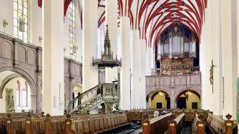 Auf unserer Gruppenreise mit Studiosus bewundern wir die Innenansicht der Thomaskirche in Leipzig, mit Blick auf die Kirchenbänke, die Kanzel und die Orgel. Ein kulturelles Highlight unserer Städtereise nach Leipzig.