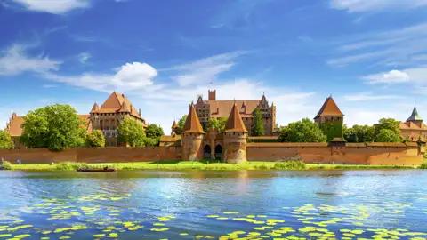 Die imposante Backsteingotik der Marienburg in Malbork, UNESCO-Welterbe, am Ufer des Flusses Nogat in Polen, ein Highlight unserer Gruppenreise mit Studiosus.