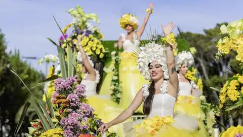 Auf unserer Gruppenreise mit Studiosus bewundern wir Tänzerinnen in aufwendigen gelben Blumenkostümen winken von einem prächtigen Festwagen beim Blumenfest in Funchal.