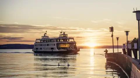 Passagierschiff mit Reisegästen auf dem Bodensee bei Sonnenuntergang auf dem Weg zur Seebühne in Bregenz, ein Highlight unserer Studiosus Gruppenreise.