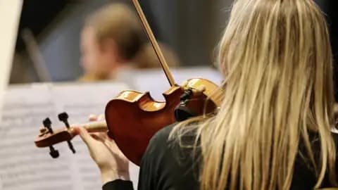 Rückansicht einer blonden Geigerin, die während eines Konzerts des Chopin-Festivals in Marienbad konzentriert Geige spielt.
