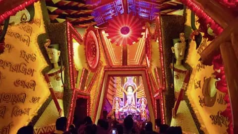 Während unserer Eventreise mit Studiosus sehen wir Gläubige und Reisende vor einem prächtigen, rot-goldenen Pandal mit der Statue der Göttin Durga während der Durga Puja in Kolkata.